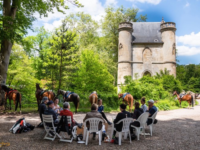 Horse riding holidays in France - people sitting in front of a castle with horses
