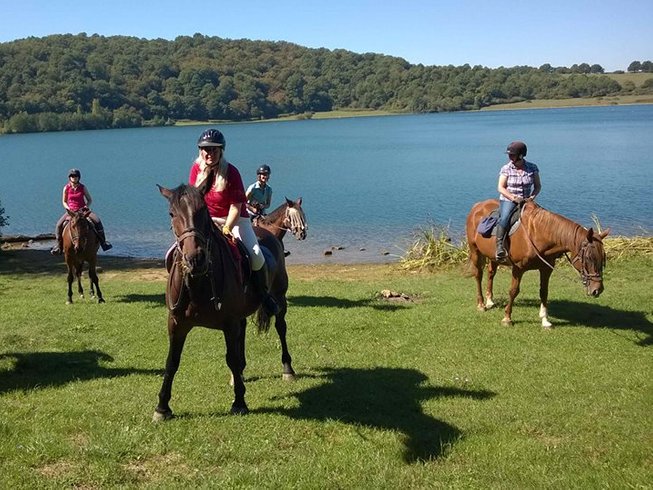People riding horses in front of the lake during horse riding holidays