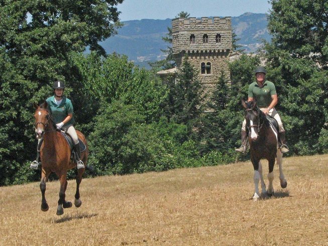 Horse riding holidays in Italy - People riding in a field with a castle in the background
