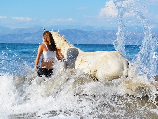 Horse riding holidays in Greece: Lady sminning with a white horse