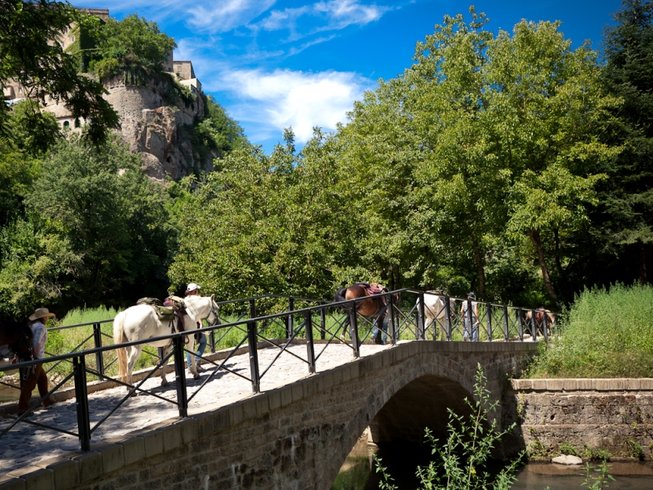 people riding horses in Tuscany on a bridge