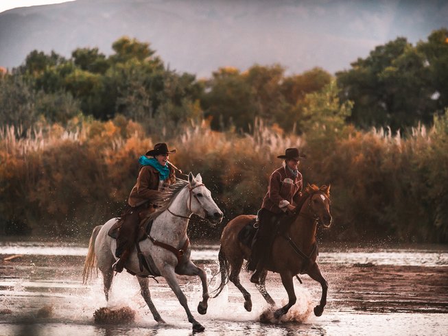 people galloping in a water stream during a ranch vacation in new mexico